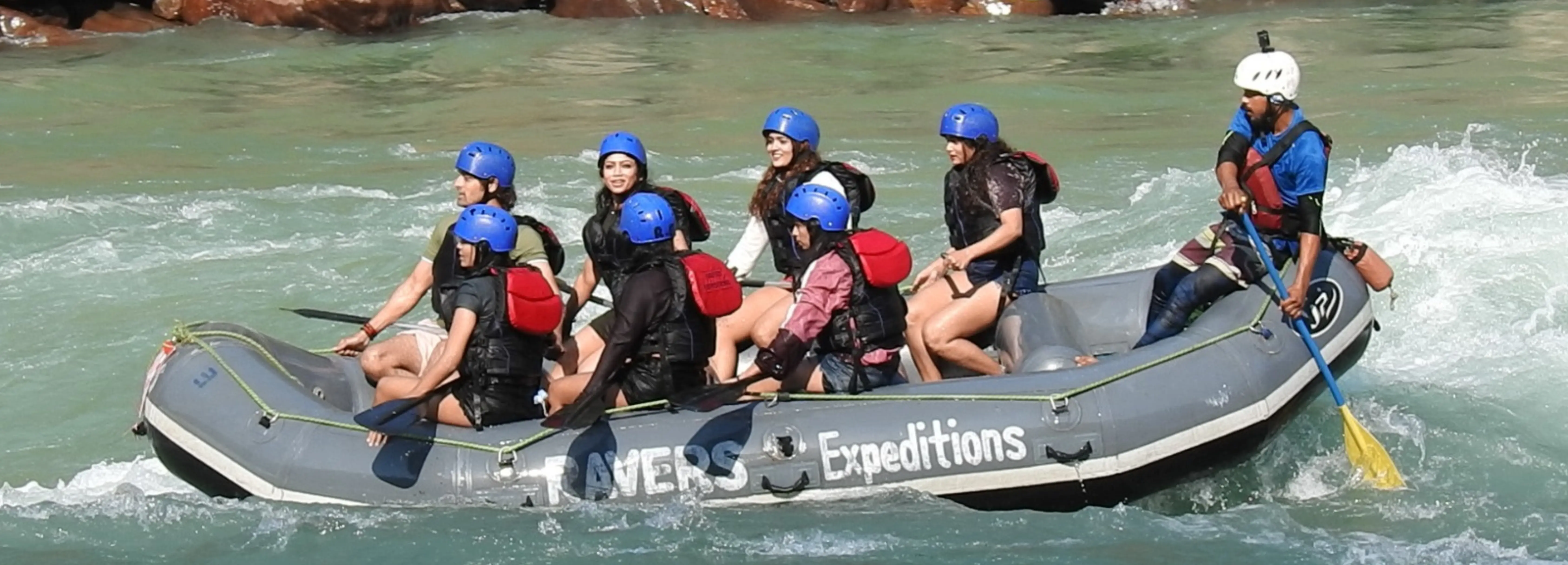Adventurers conquering thrilling rapids during a 24 km river rafting expedition in Rishikesh.